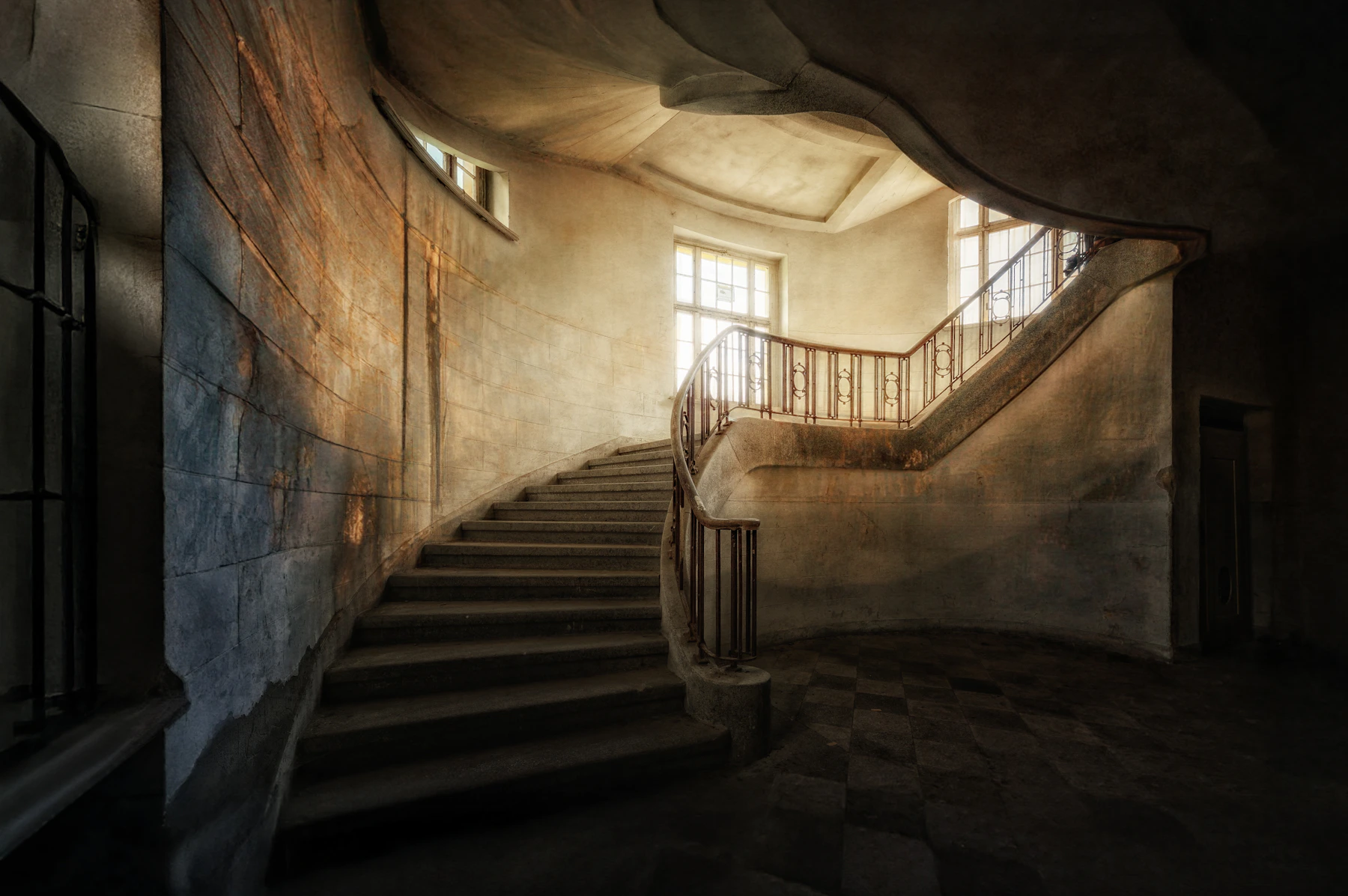 A curving stone staircase leading towards soft daylight