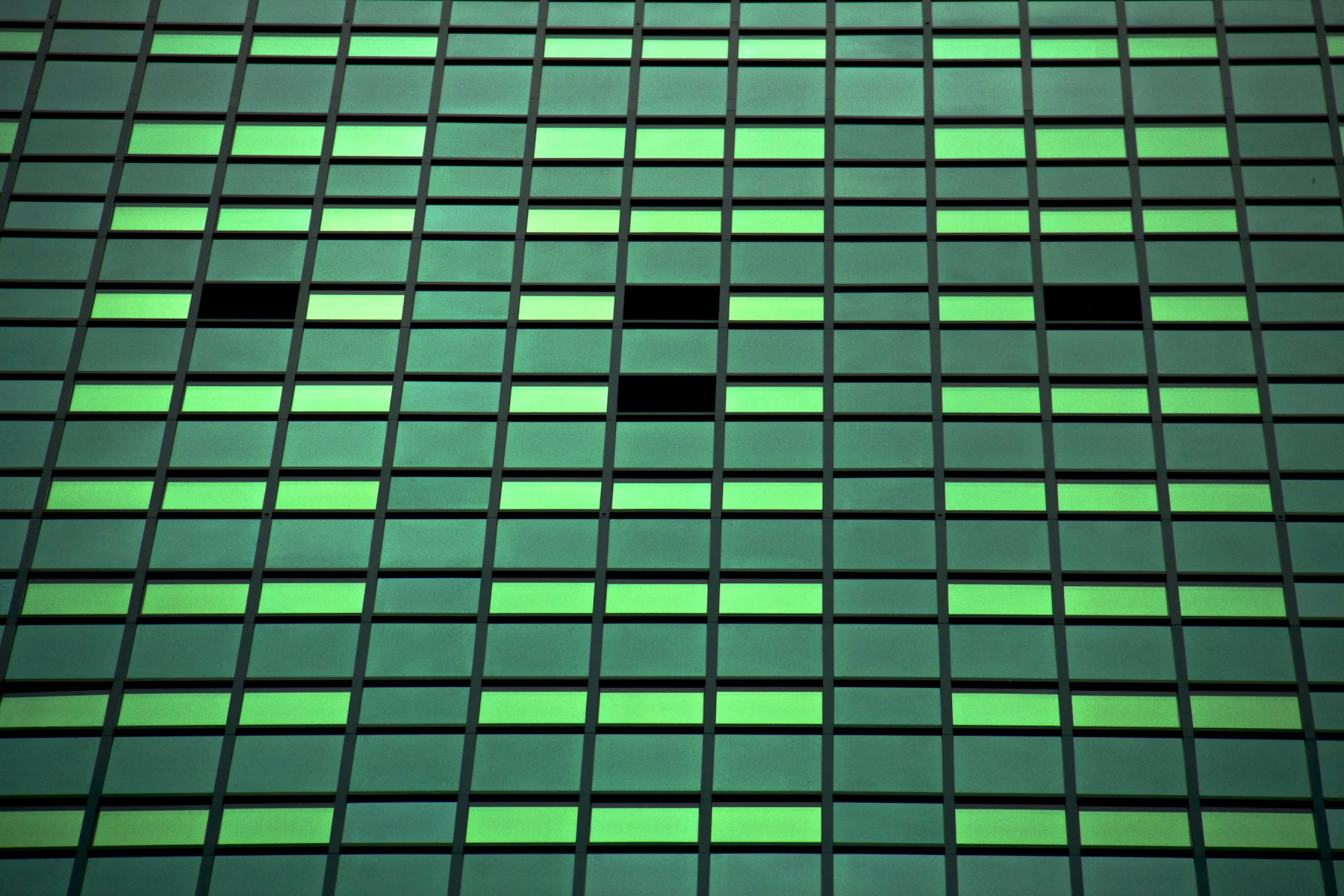 An emerald glass facade with precisely ordered structural lines