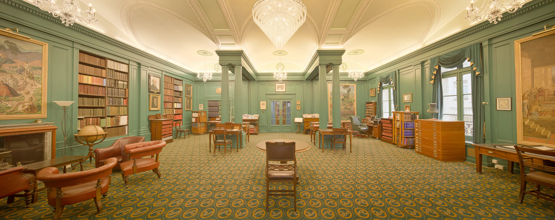 A green reading room with carefully organised shelves and warm wood